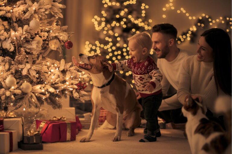 Une famille heureuse avec un enfant jouant avec un chien devant un sapin de Noël décoré, symbolisant la magie des fêtes avec les animaux domestiques.