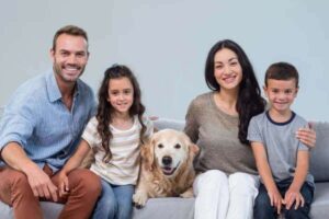 Une famille souriante posant avec leurs chiens et chats, illustrant le concept de "pet parents" où les animaux sont considérés comme des membres de la famille.