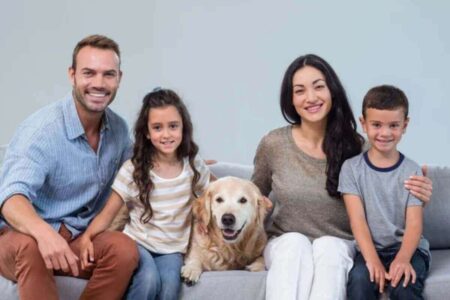 Une famille souriante posant avec leurs chiens et chats, illustrant le concept de "pet parents" où les animaux sont considérés comme des membres de la famille.
