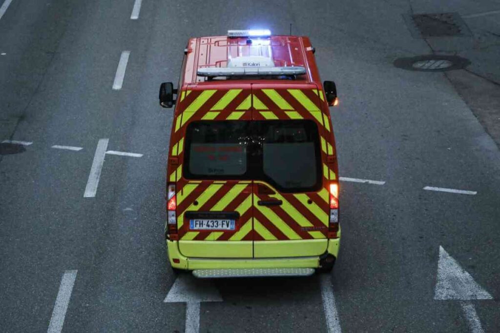 Ambulance garée dans une rue sombre, vue de l'arrière, symbolisant une intervention d'urgence suite à un drame familial.