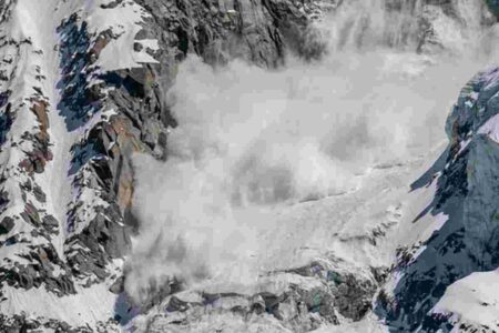 Secouriste et chien de sauvetage fouillant dans une zone de montagne enneigée après une avalanche en Norvège