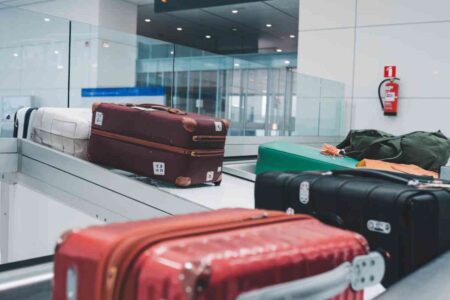 Valises en transit sur un tapis roulant dans une zone de tri d’un aéroport, symbolisant les systèmes logistiques automatisés.