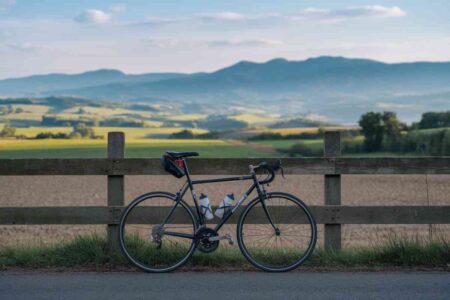 Cycliste sur une route de campagne avec un paysage vallonné en arrière-plan