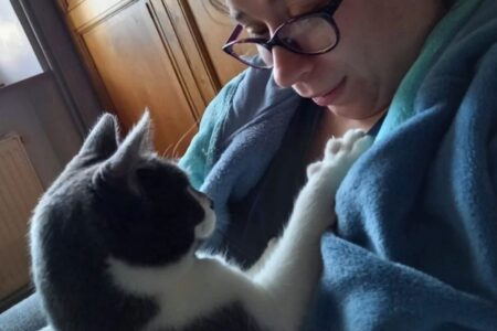Katia Guillet en interaction douce avec un chat, regard croisé et patte posée sur sa poitrine