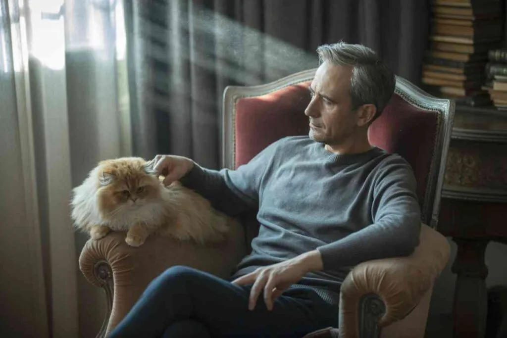 Un homme pensif assis près d’un chat calme et silencieux, illustrant une situation où le chat ne miaule plus.