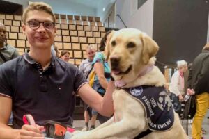 Jeune homme en fauteuil roulant souriant avec un chien d’assistance labrador lors de la cérémonie Handi’Chiens à Laval