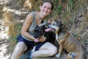 Elisabeth Sandrin entourée de deux chiens pendant une balade, un moment complice au cœur de son approche en communication animale.