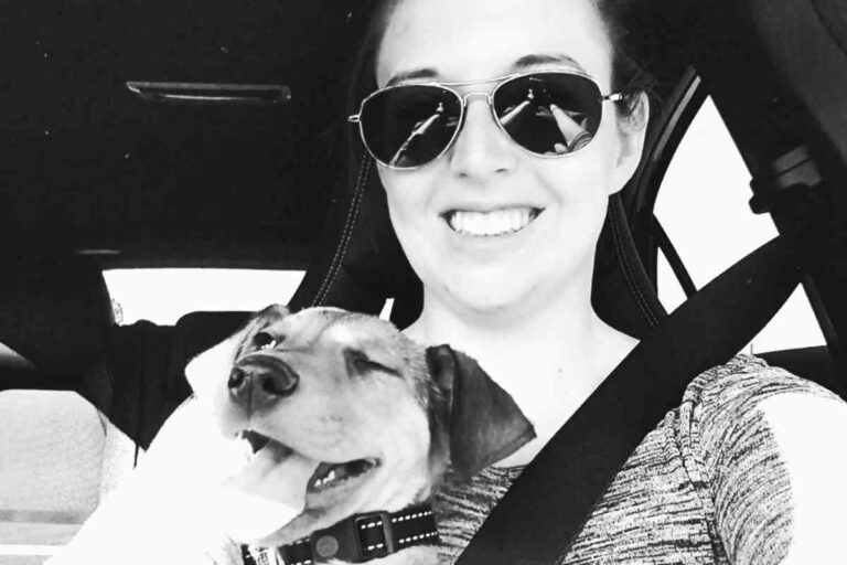 Camille souriante dans une voiture, tenant son chien heureux contre elle.
