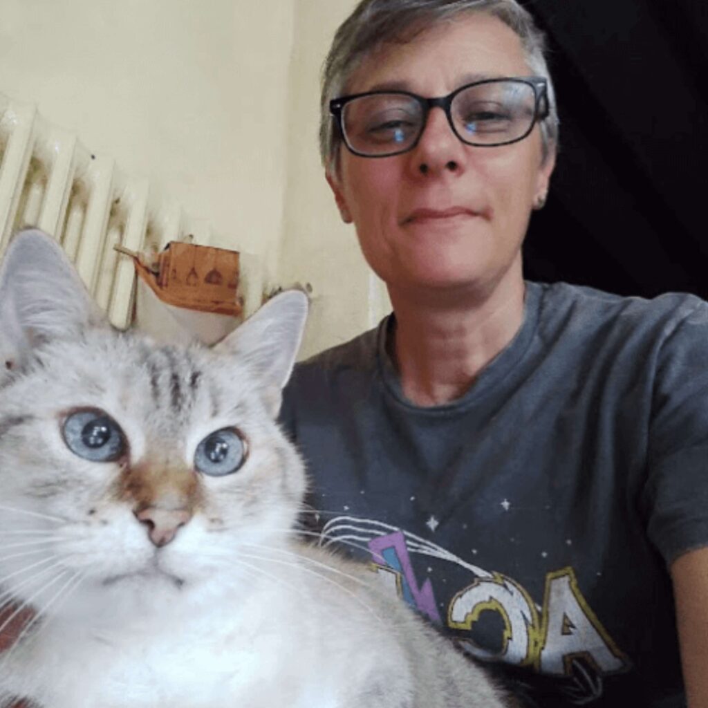 Portrait de Laëtitia Verneau, éducatrice canine, tenant un chat gris aux yeux bleus dans ses bras