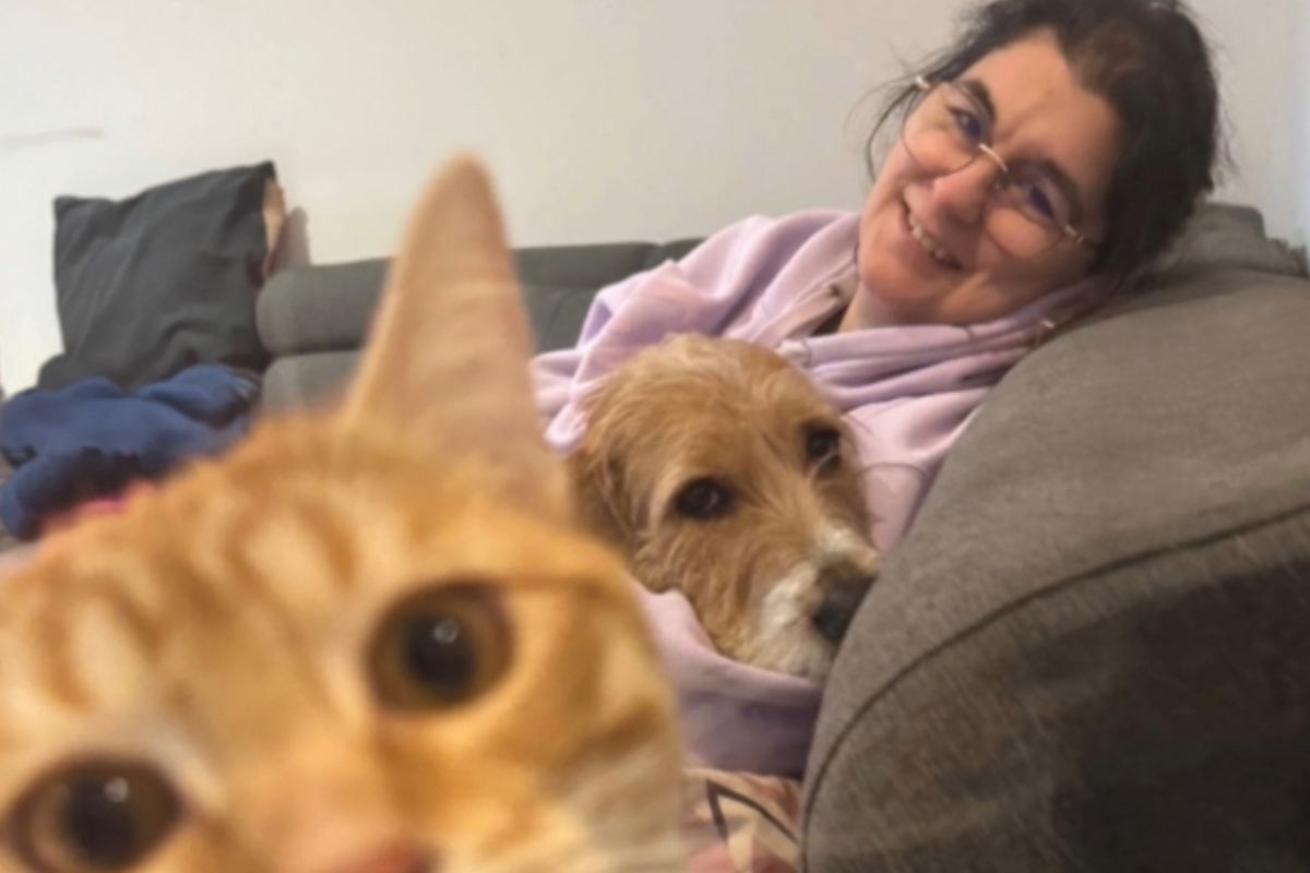 Rachel Perruchet souriante, assise sur un canapé avec son chien et son chat