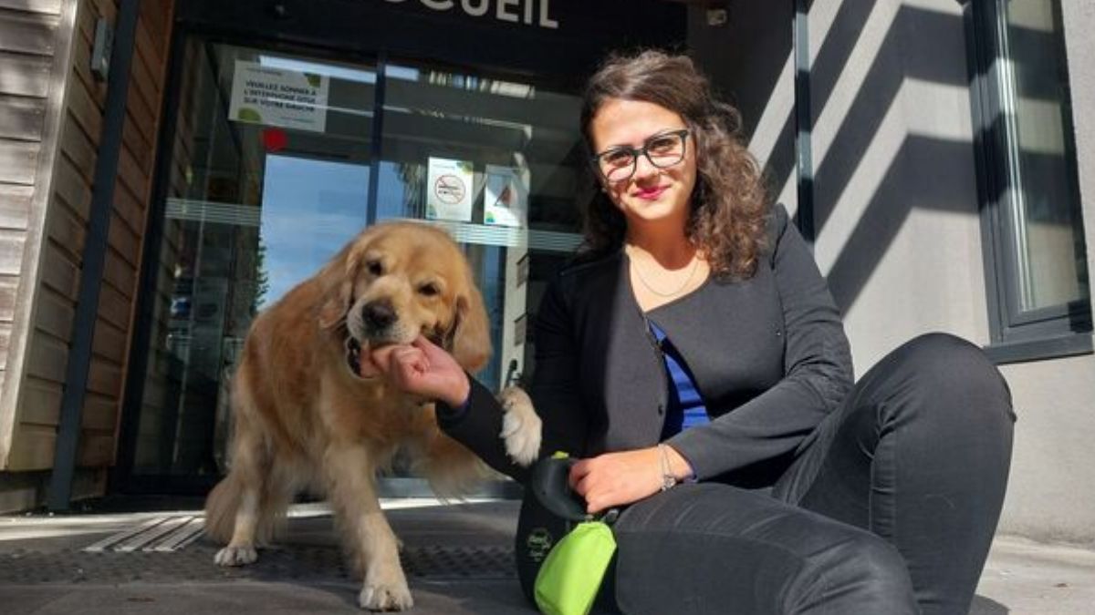 Une employée municipale assise devant la mairie de Pomponne avec son chien, symbole de la nouvelle initiative permettant aux agents de venir travailler avec leurs animaux.