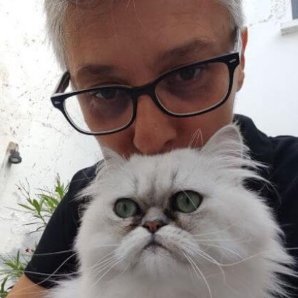 Laëtitia Verneau educatrice a Angers portant des lunettes tenant un chat blanc au pelage long, les deux regardant l’objectif.
