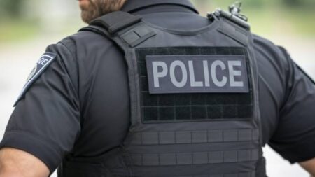 Policier vu de dos portant un gilet marqué « Police » lors d’une intervention. Illustration du lien entre ordre et tension lors d’une interpellation.